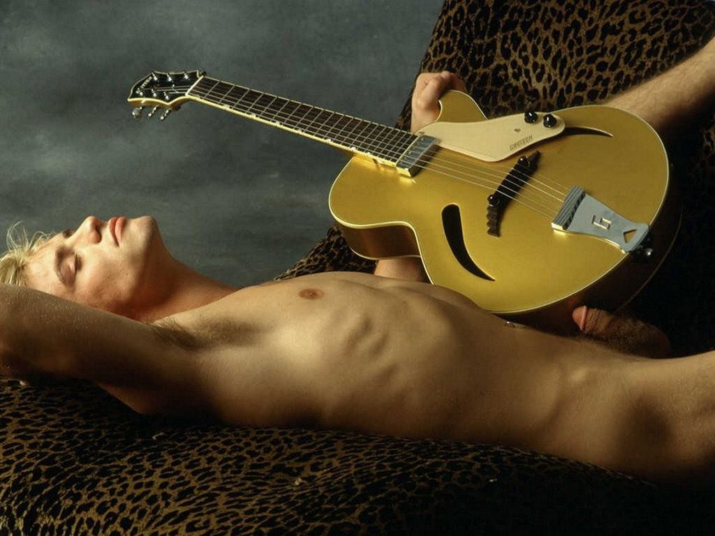 голый парень лежит с гитарой упираясь в нее сморщенным пенисом, фото красив...