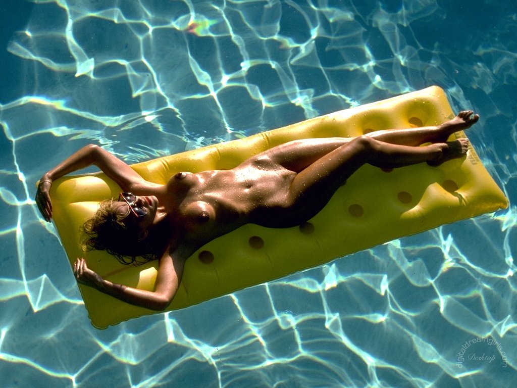 длинноногая голая девушка загорает в бассейне лежа на надувном матрасе, фото