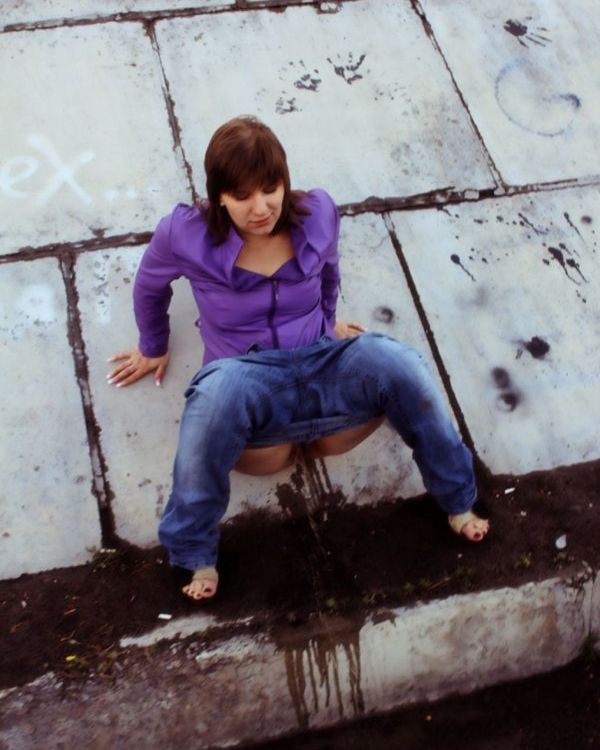 девушка в джинсах писает у бетонной стены, фото писсинга, золотой дождь фото