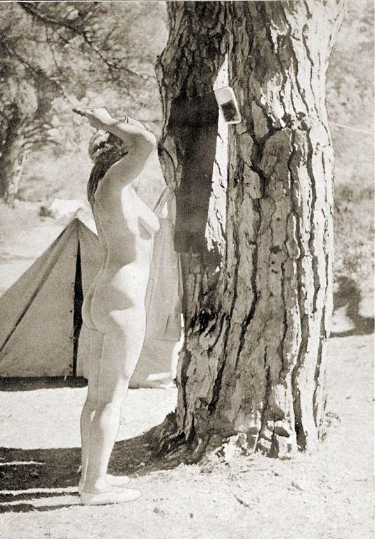 голая туристка причесывается стоя перед прибитым к дереву зеркальцем, ретро фото голой мамы