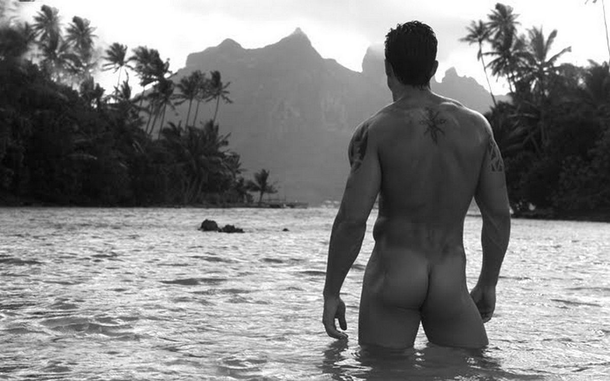 голый мужчина в татуировках стоит в морской воде между тропическими островами, фото красивого мужчины
